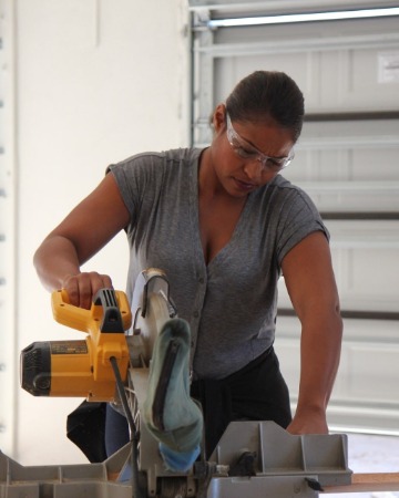 Mika using machine to cut wood at 100 Day Dreams Home.